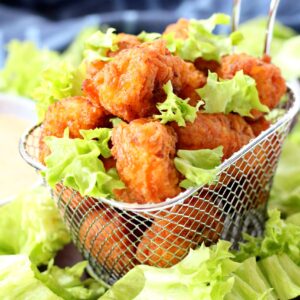 Homemade popcorn chicken in mini fryer basket garnished with broken up lettuce
