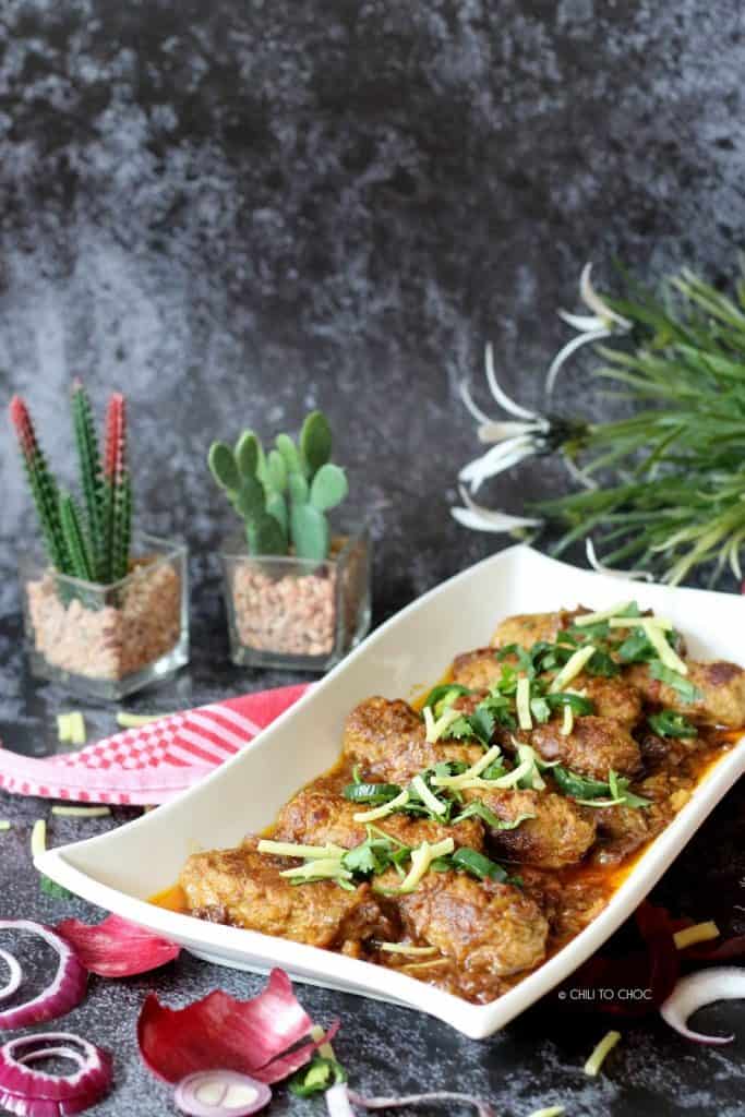 Beef kabab curry in a white serving dish with garnishes on top