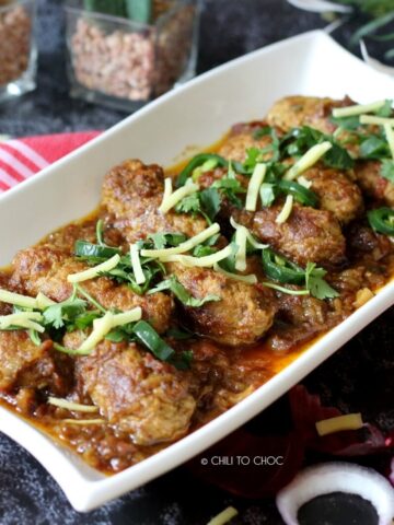 Seekh Kabab Masala on a white dish garnished with ginger slices, fresh coriander and green chilies