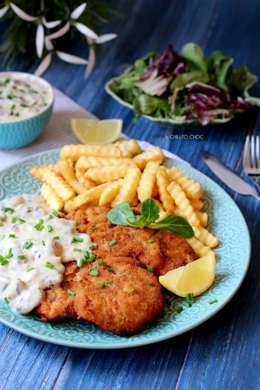 Schnitzel served with mushroom sauce, fries, lemon wedge and a salad