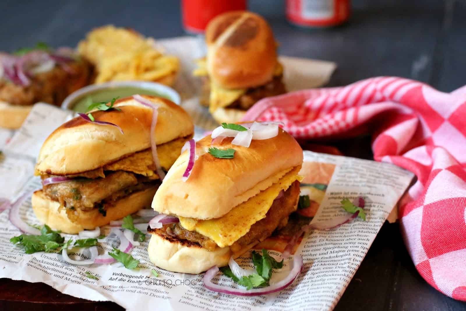 Vegetarian sandwiches on a newspaper with coriander and red onion around it and red tea towel on the side