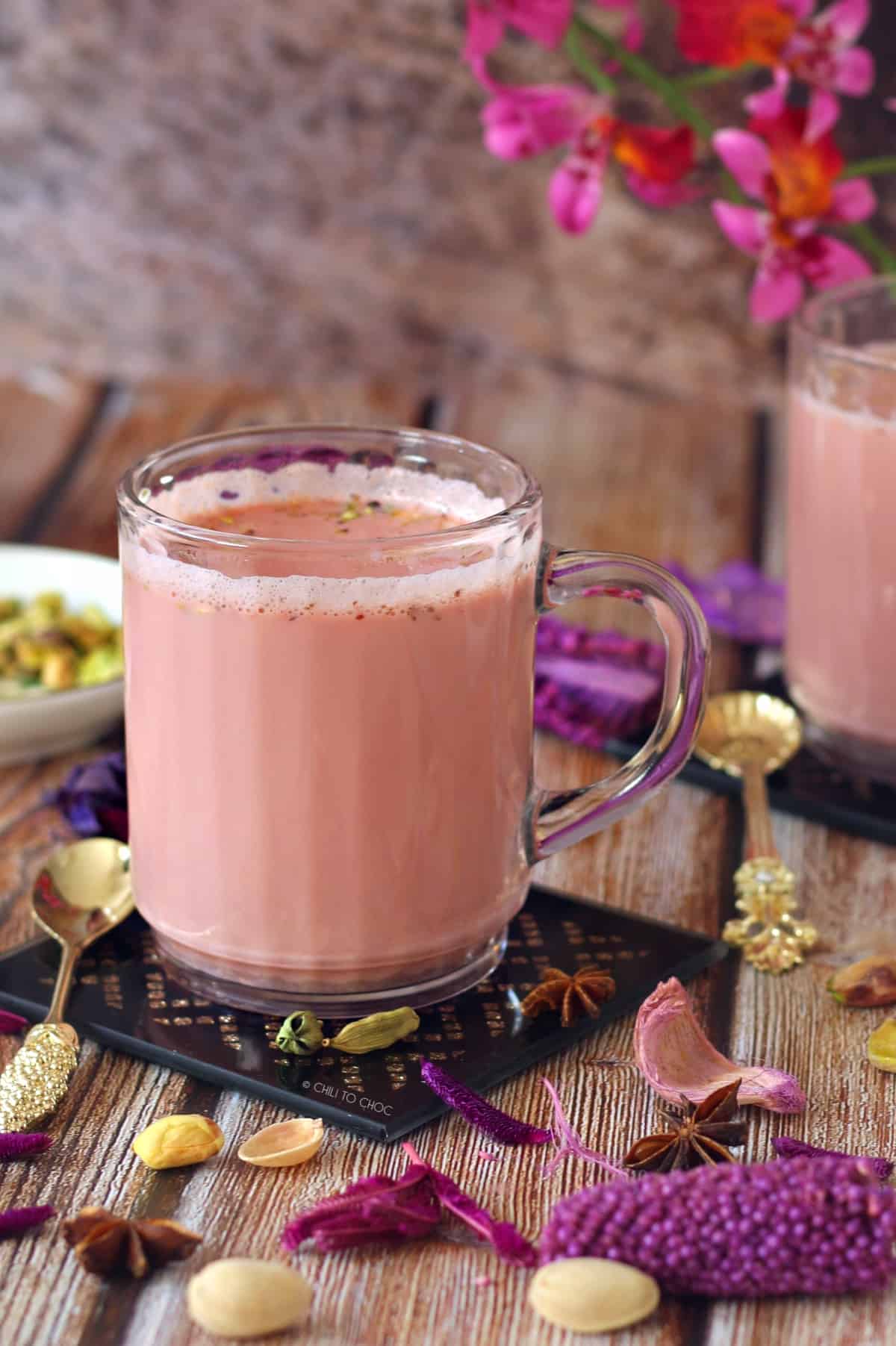 Kashmiri Pink Tea in a clear mug with decoration around it