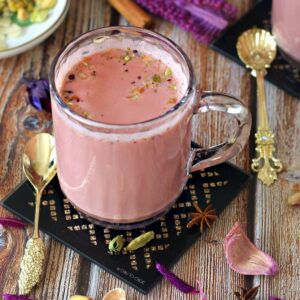 Kashmiri Pink Chai in a clear mug on a black coaster