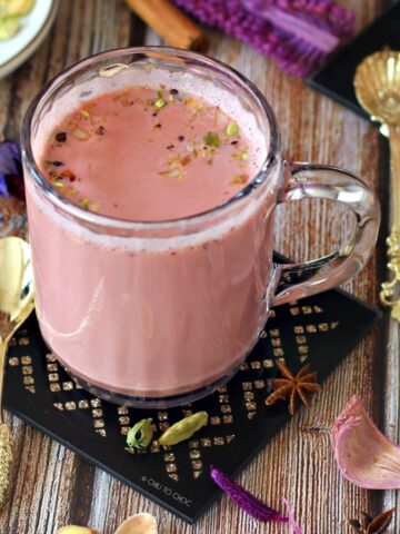 Kashmiri Pink Chai in a clear mug on a black coaster