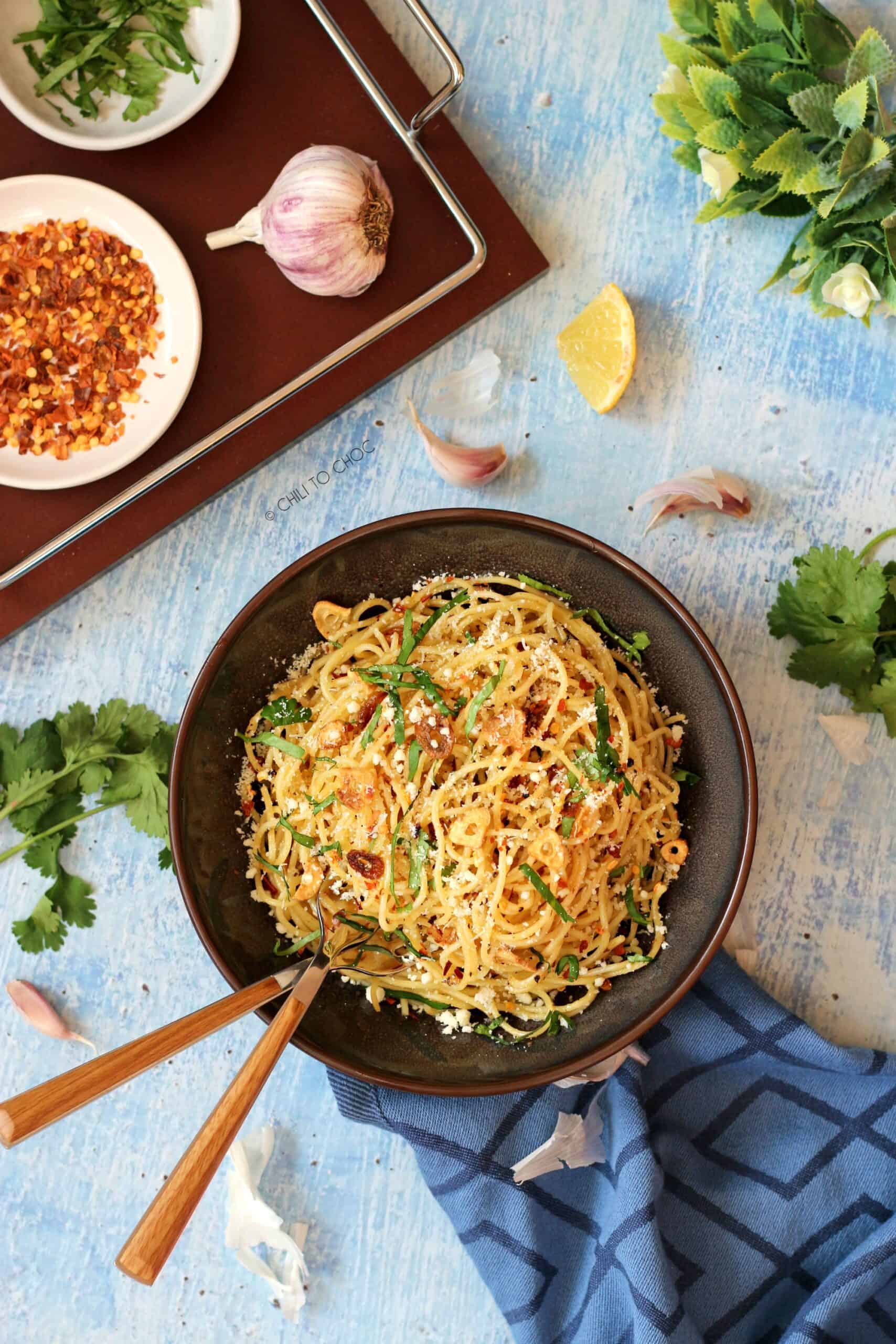 Spaghetti Aglio E Olio Spaghetti in a deep dish with two works inside it and garnishes on the side