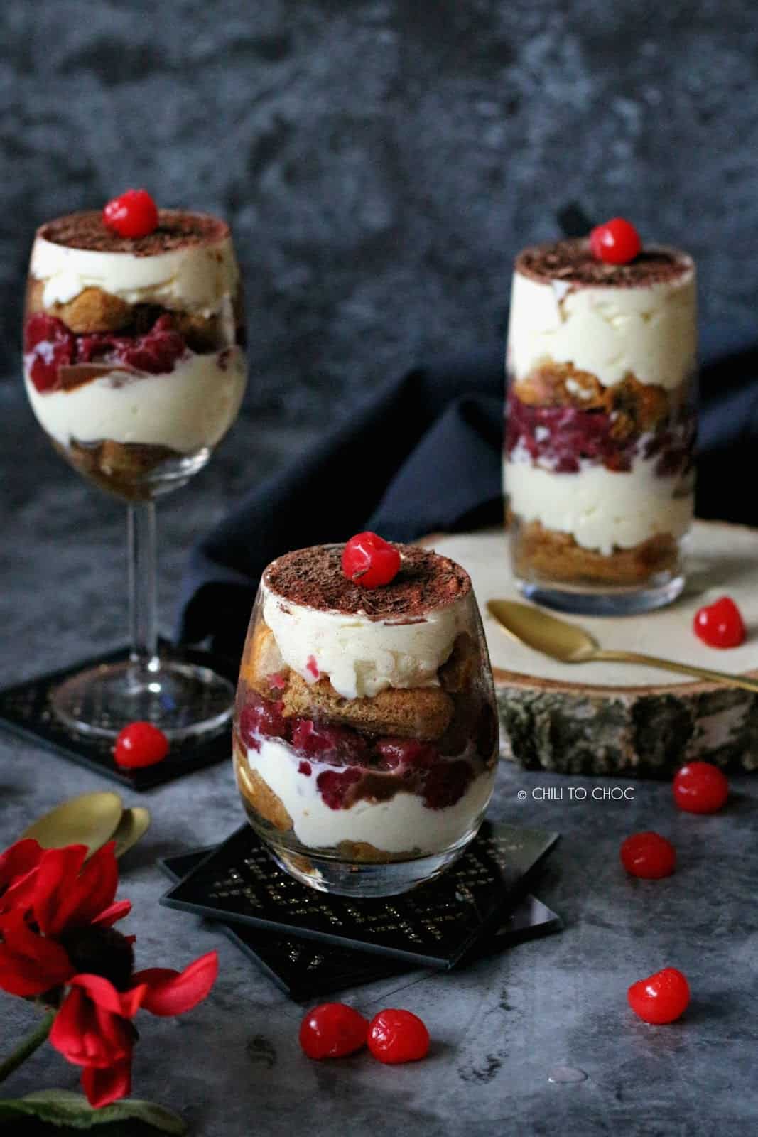 Three glasses of black forest tiramisu topped with a maraschino cherry