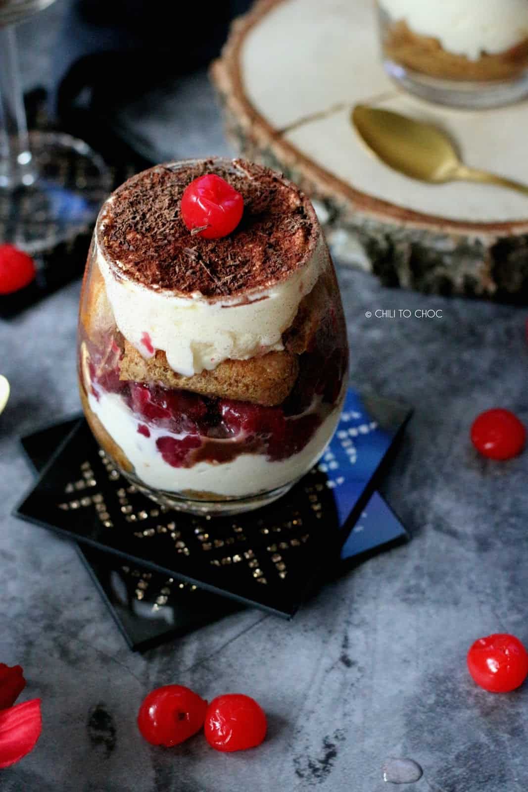 Three glasses of black forest tiramisu topped with a maraschino cherry