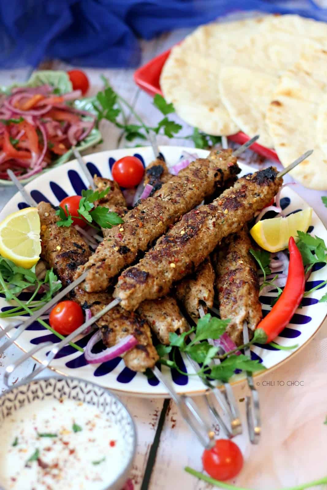 Turkish Lamb Adana Kebab on a plate garnished with lemon wedges, cherry tomatoes and parsley