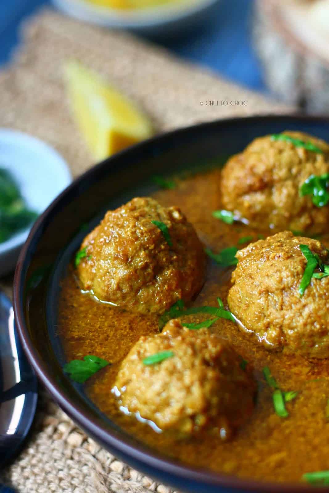 Closeup shot of meatballs in a curry with chopped cilantro on top.