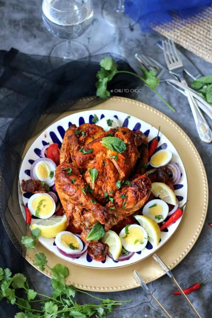 Murgh Musallam (Mughal-Style Stuffed Whole Chicken) Whole chicken with mint and coriander garnish, surrounded by sliced hard boiled eggs