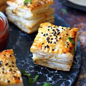 Pakistani chicken patties topped with sesame seeds on a marbled black tray