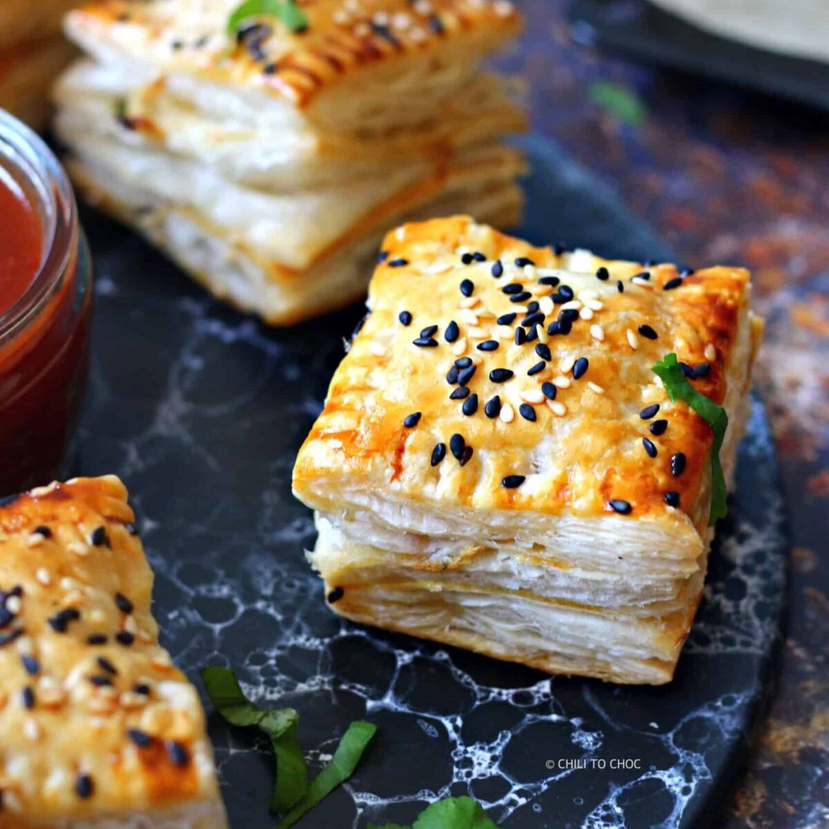 Pakistani chicken patties topped with sesame seeds on a marbled black tray