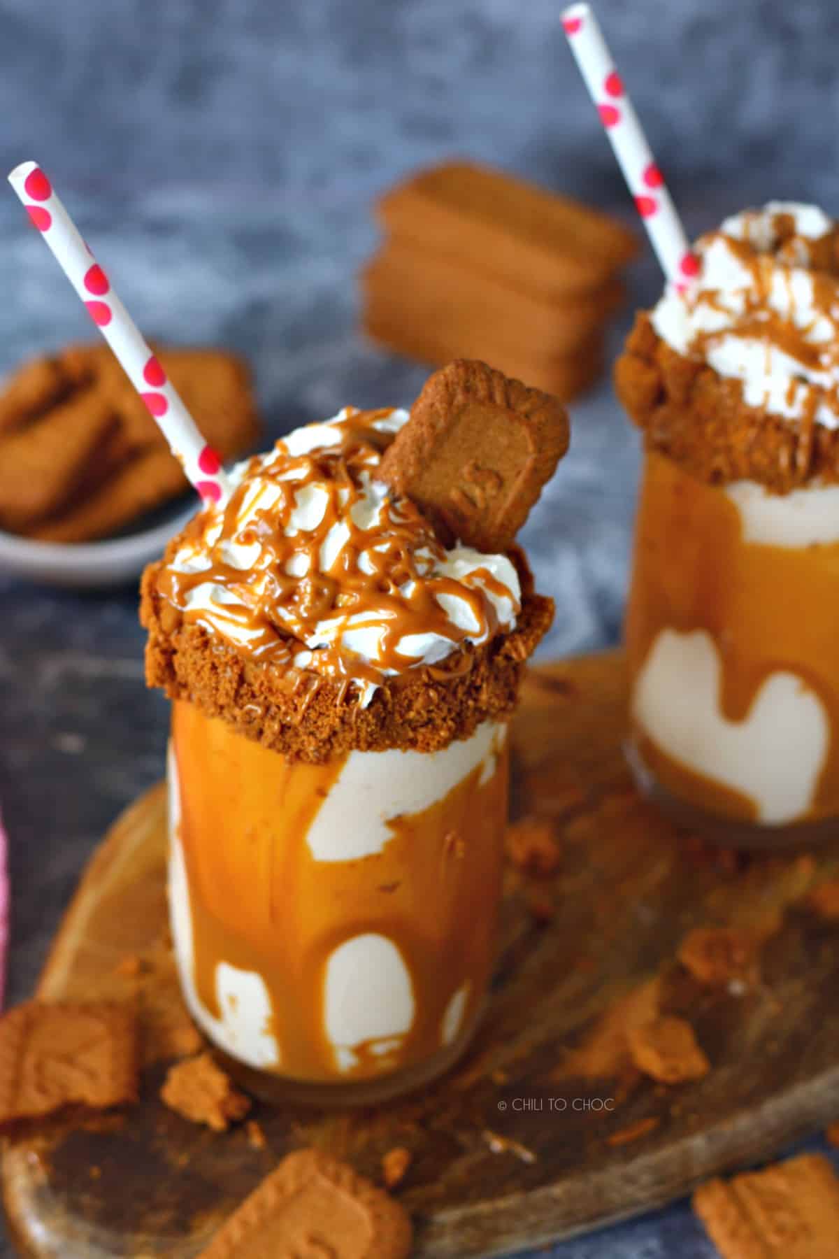 Two decorated glasses of Biscoff milkshake with polka dots straws.