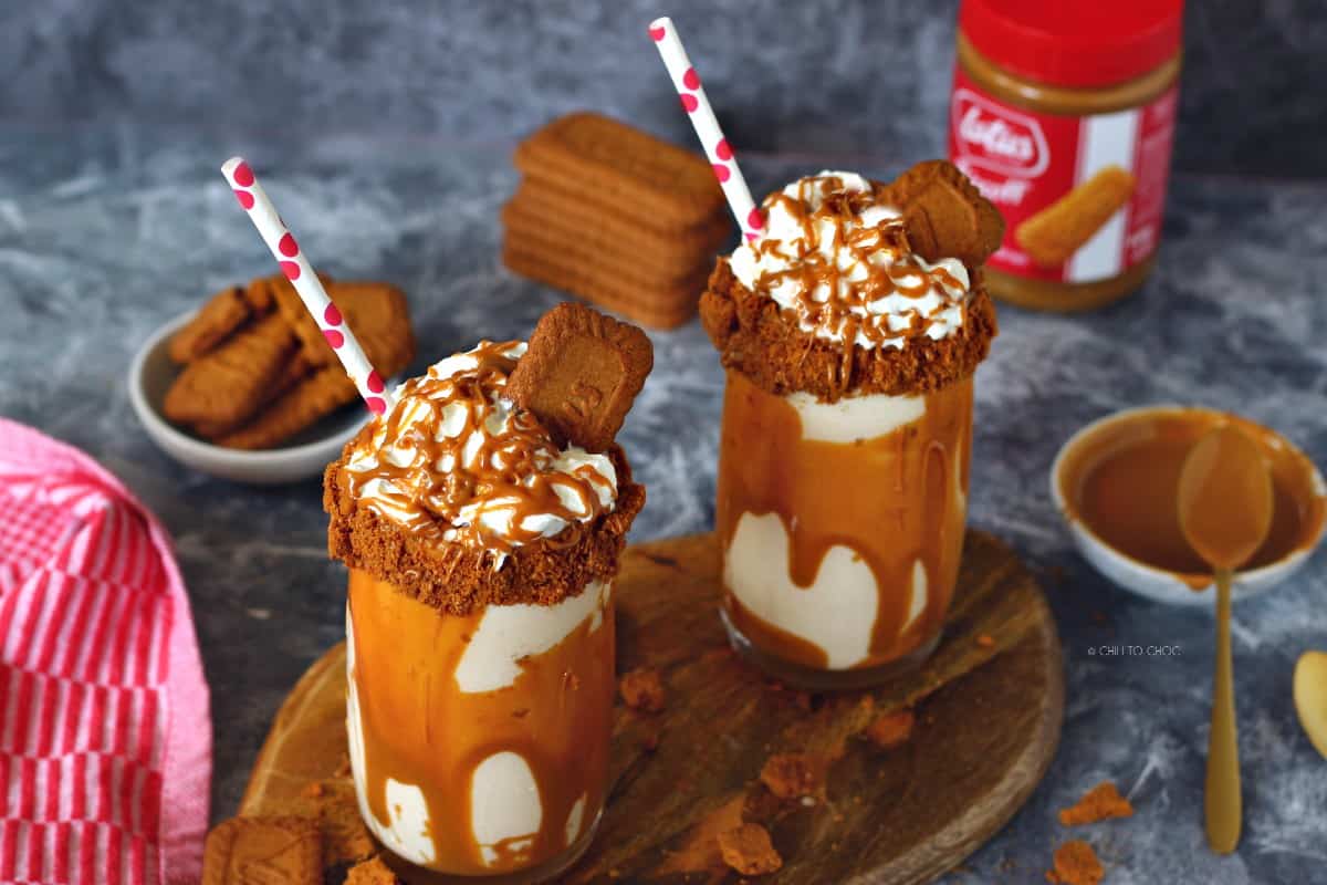 Decorated Biscoff milkshake on a wooden board on an aesthetic backdrop.