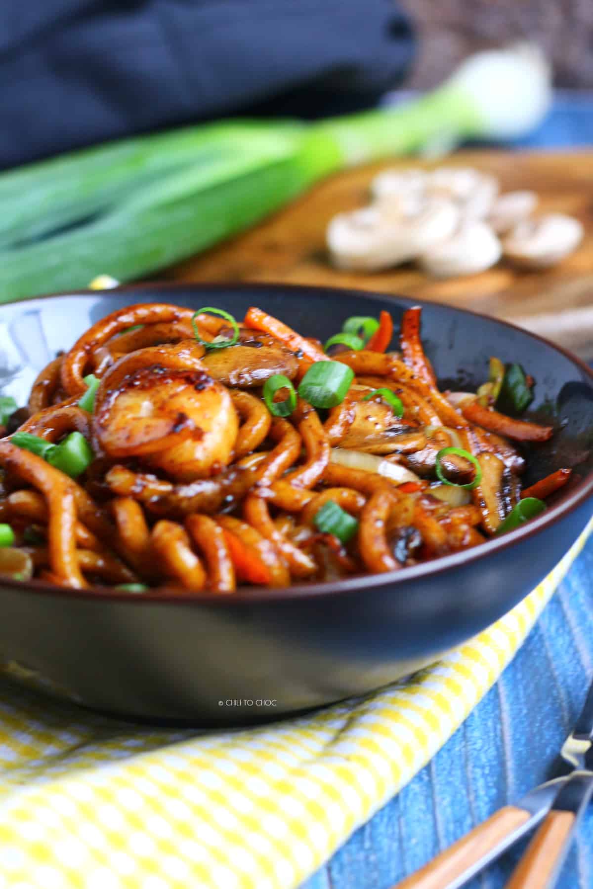 Udon noodleswith shrimps and spring onion in a deep black dish