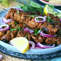 Bihari Kabab garnished with lemon wedges, red onion and fresh coriander