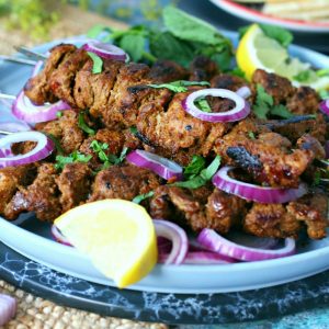 Bihari Kabab garnished with lemon wedges, red onion and fresh coriander