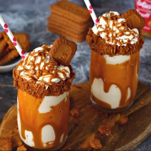 Two loaded biscoff milkshake glasses with straws.