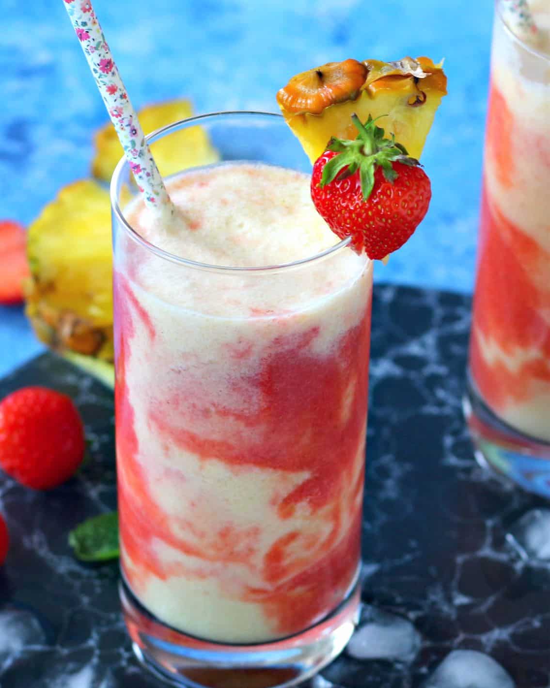 Glass of Strawberry Pina Colada with a pineapple wedge and strawberry on top