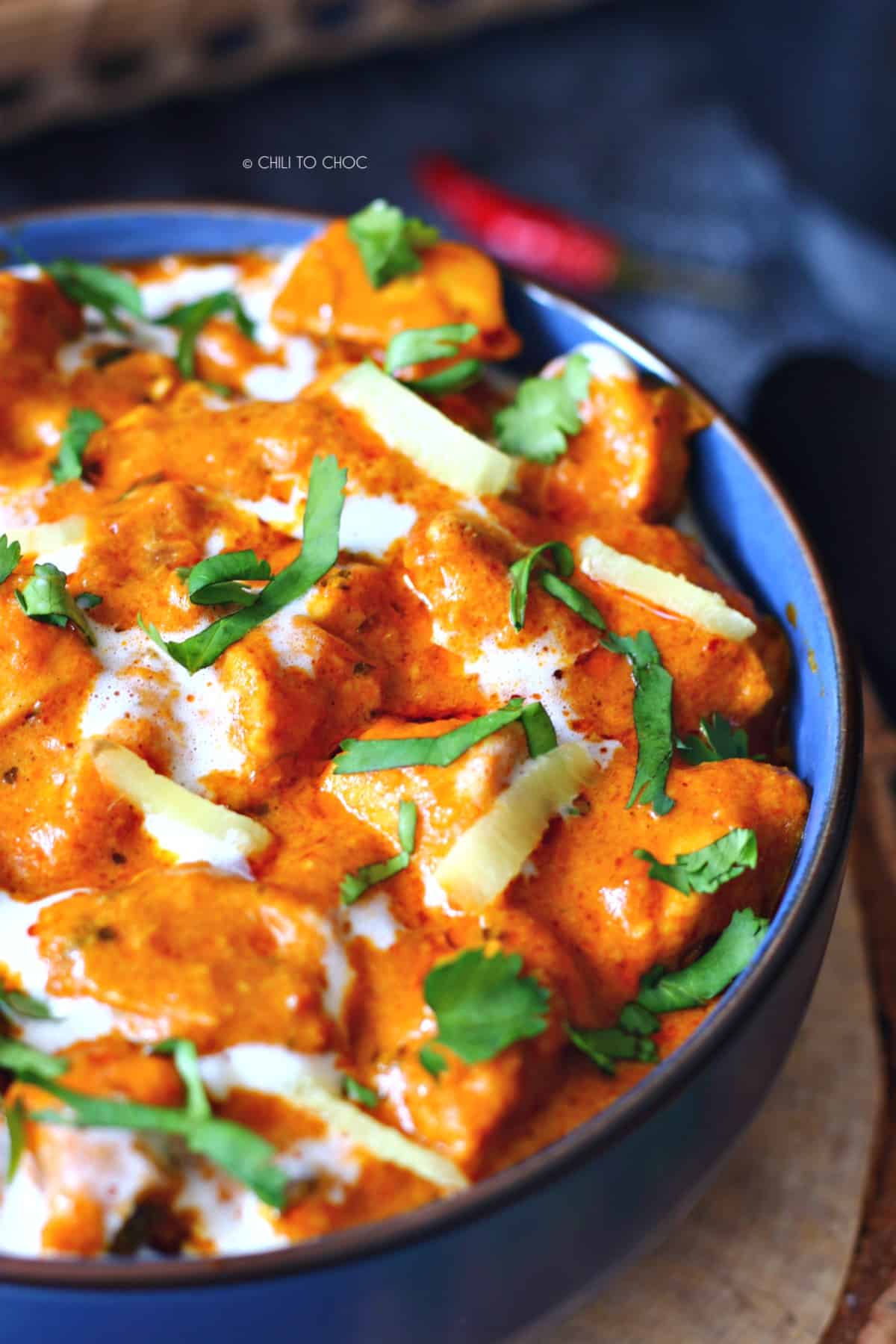 Close up of Pakistani chicken handi with sliced ginger, cream and fresh chopped coriander on top