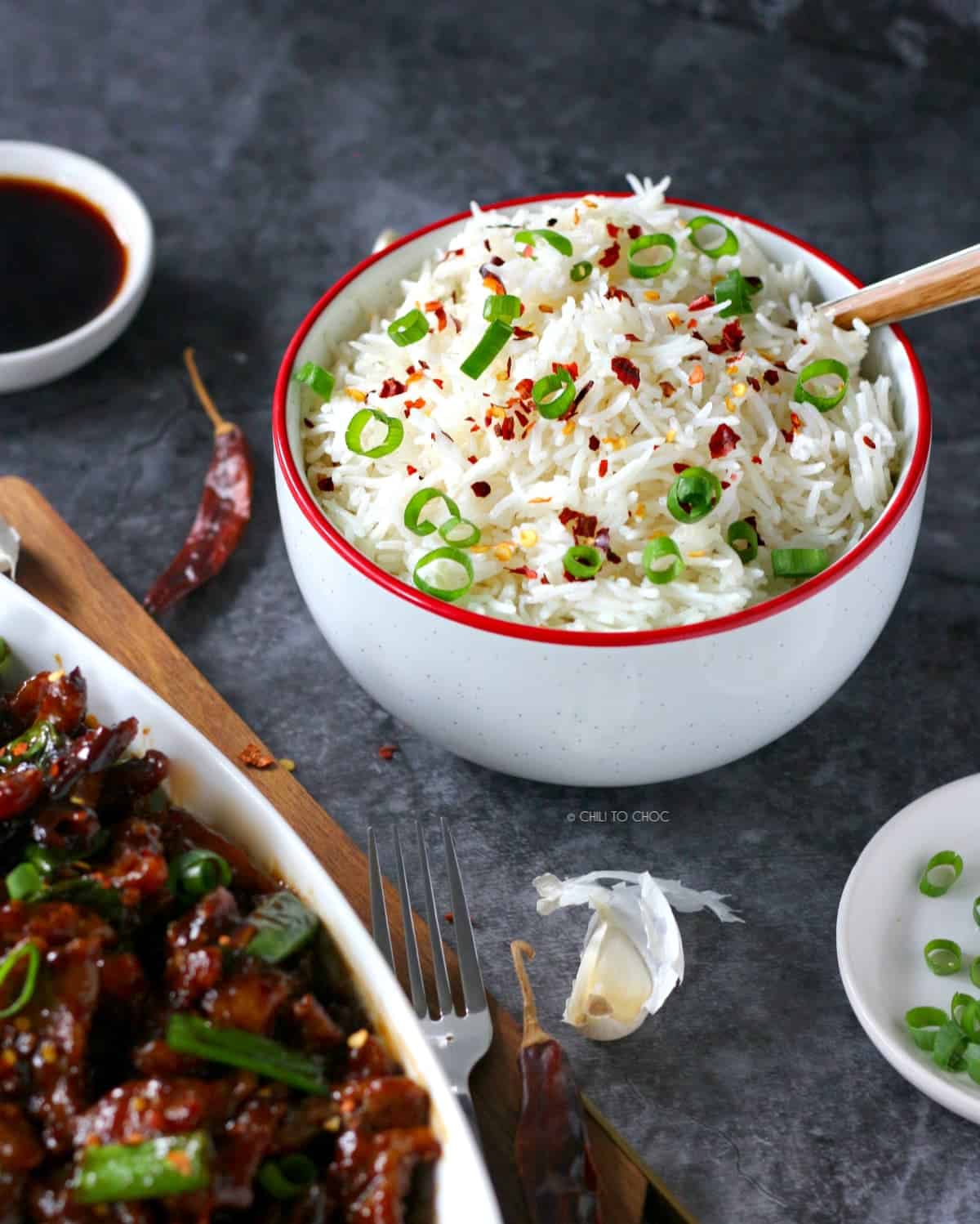 Plain rice garnished with red chili flakes and spring onion to serve alongside beef stiry fry