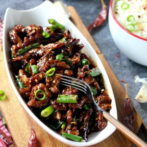 Spicy Mongolian Beef with spring onions for garnish and dried red chilies around it