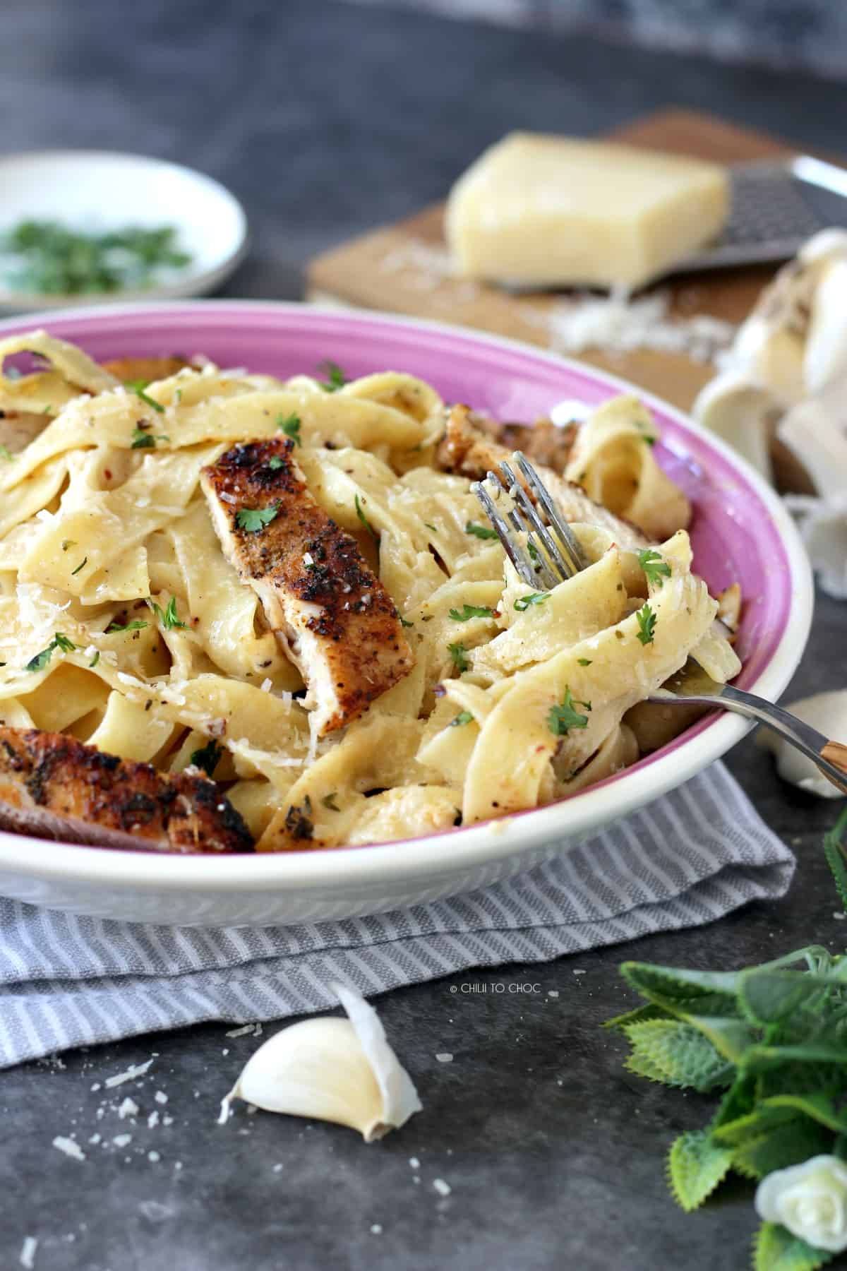 Fettucine Alfredo with grilled chicken strips in a purple plate and a fork in it