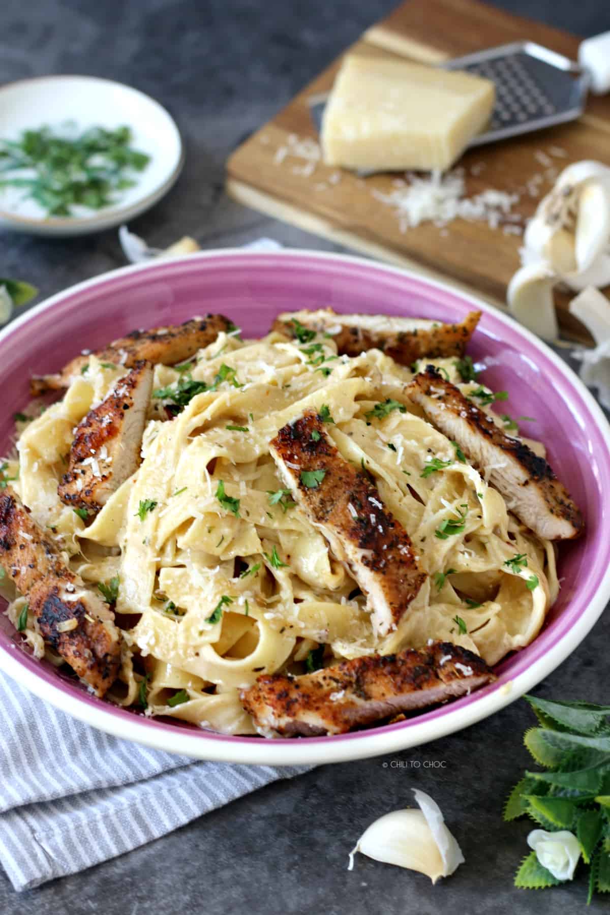 Fettuccine Alfredo pasta in a plate with grated Parmesan cheese at the back
