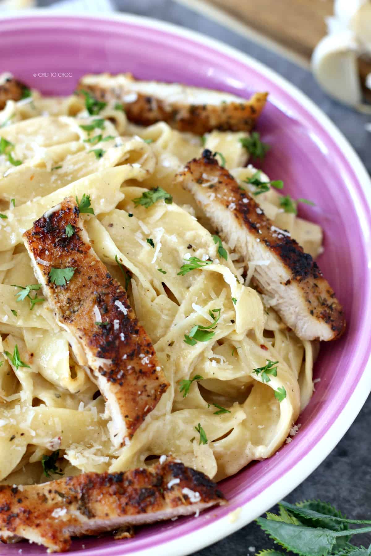 Closeup of fettuccine pasta topped with grilled chicken strips