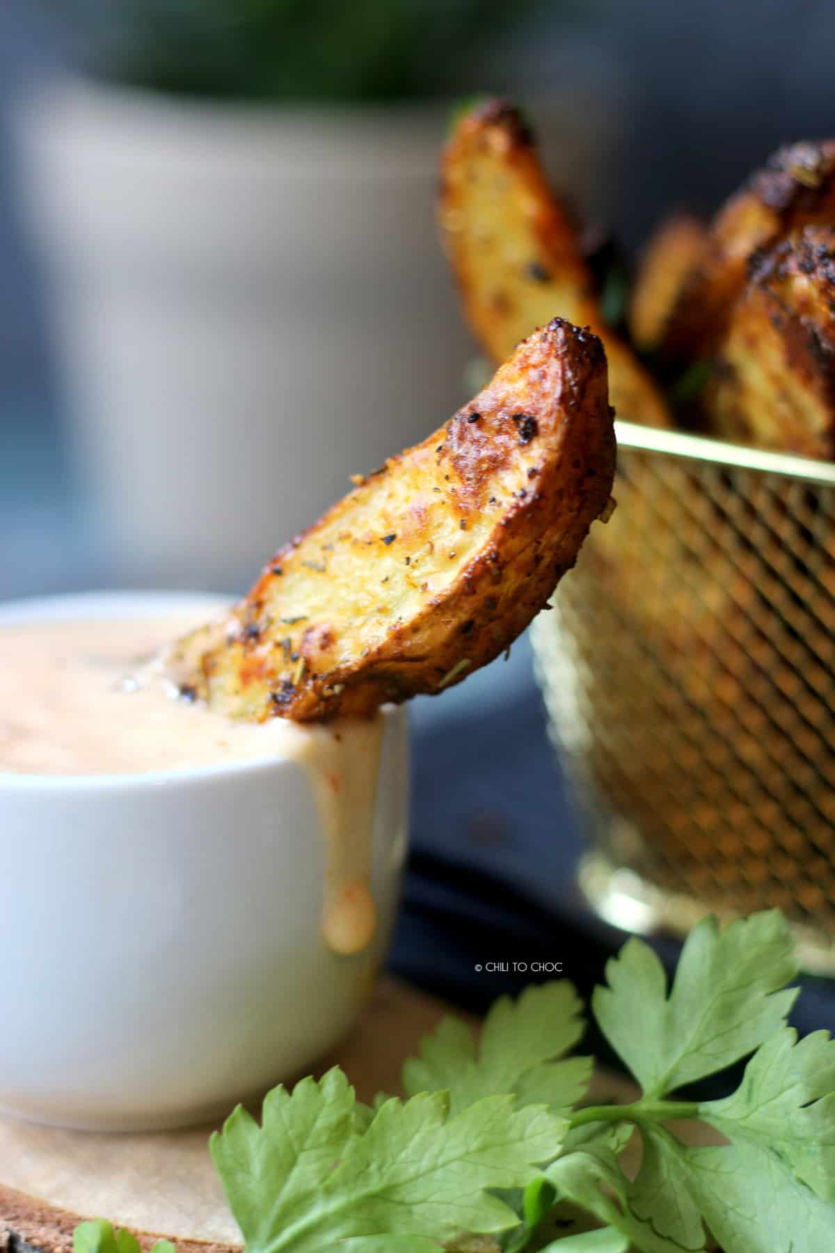 One potato wedge in a dip bowl with sauce.