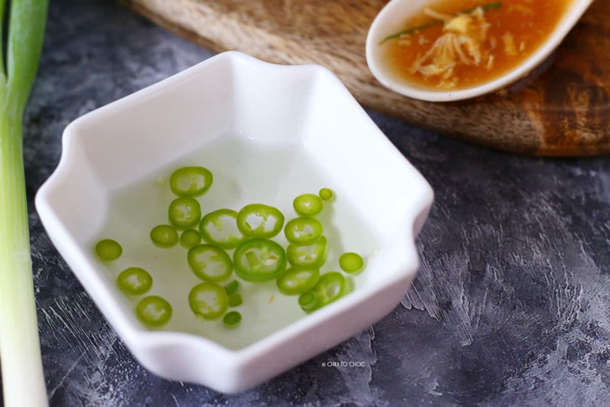 Vinegar and chili mixed in a small dip bowl along with a spoonful of soup on the side.