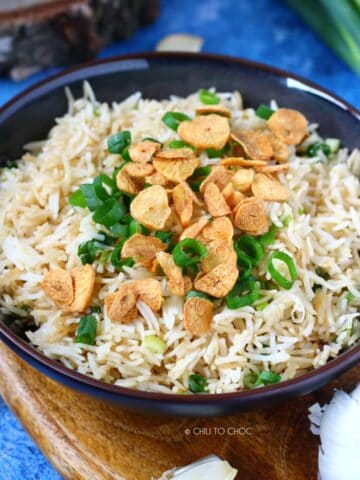 Garlic Butter Fried Rice in a shallow black dish topped with fried garlic slices and spring onion