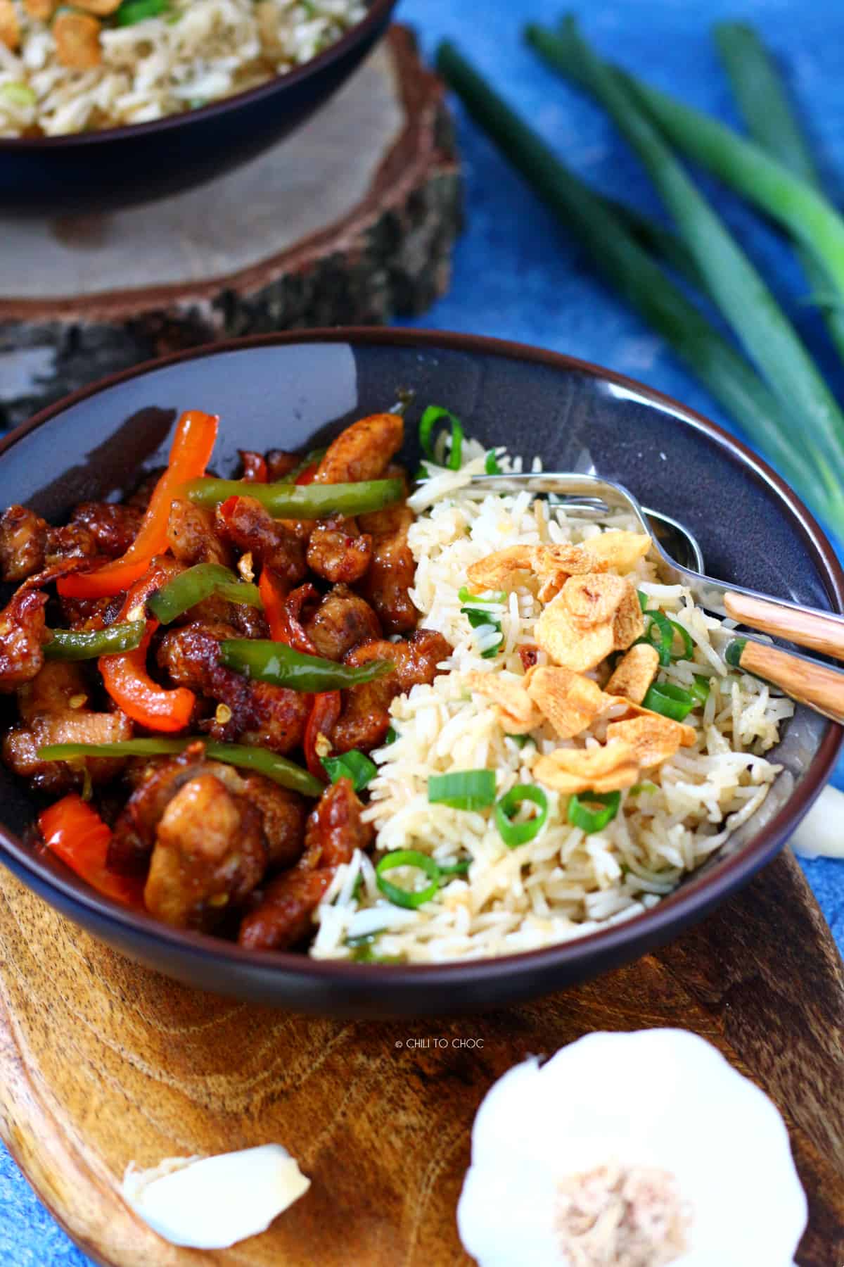 Chinese Chili Chicken with Garlic Rice in a dish with a spoon and fork on the side