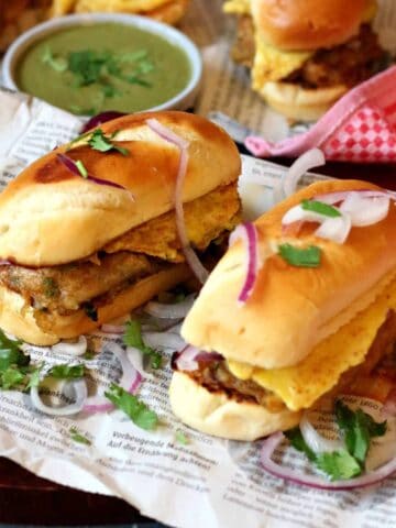 Bun Kabab on a newspaper with green chutney behind it