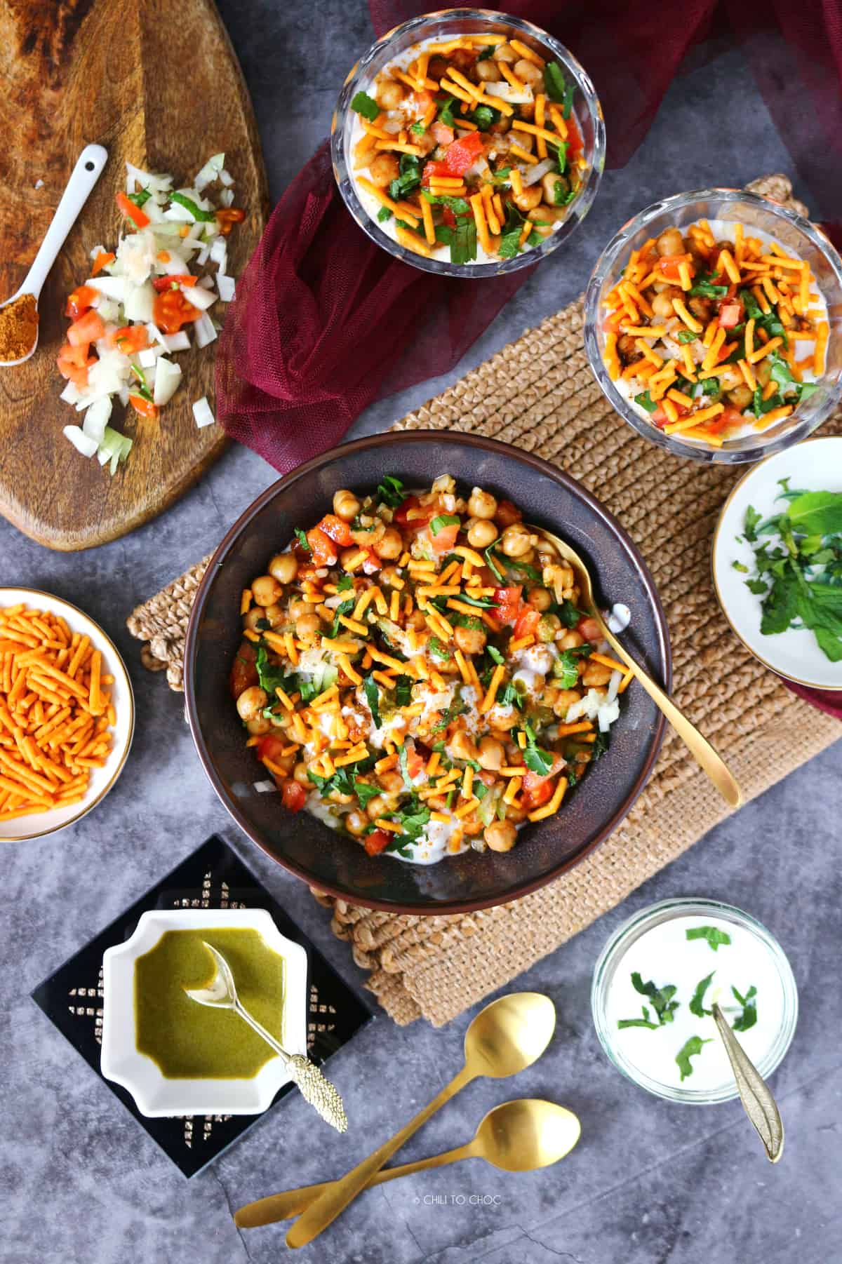 flatlay photography of chana chaat with its chutneys and ingredients all around it