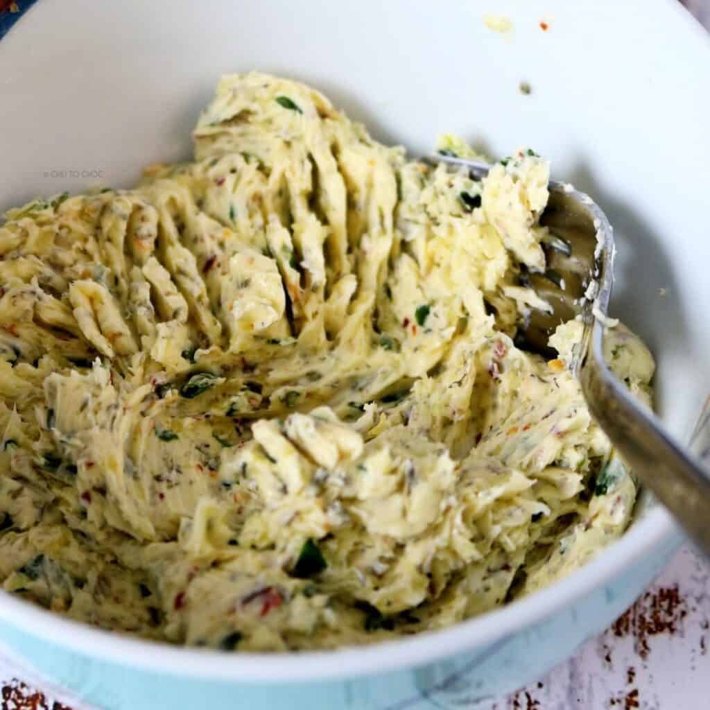 Softened garlic butter in a bowl with fork