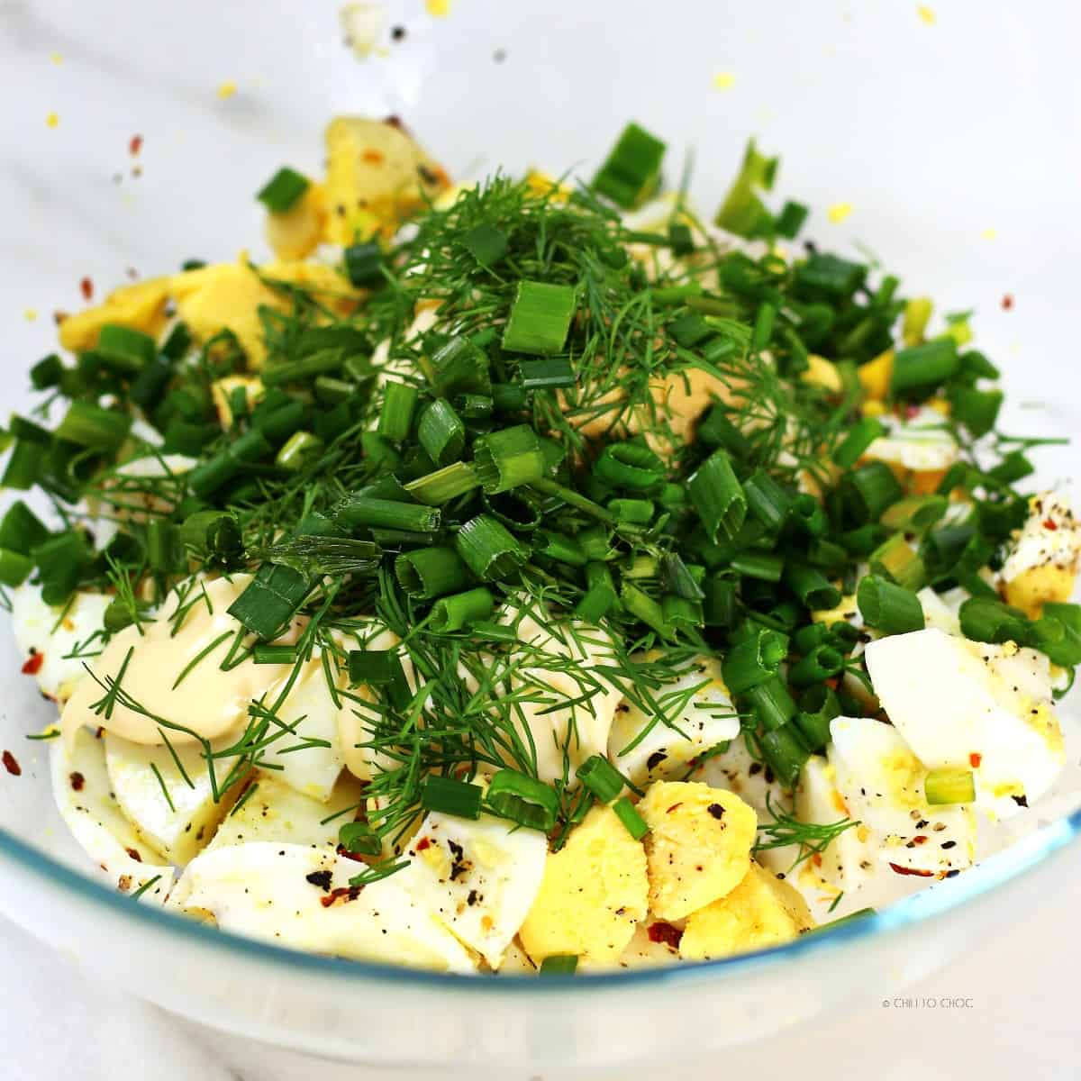 Egg salad mixture in a transparent bowl.