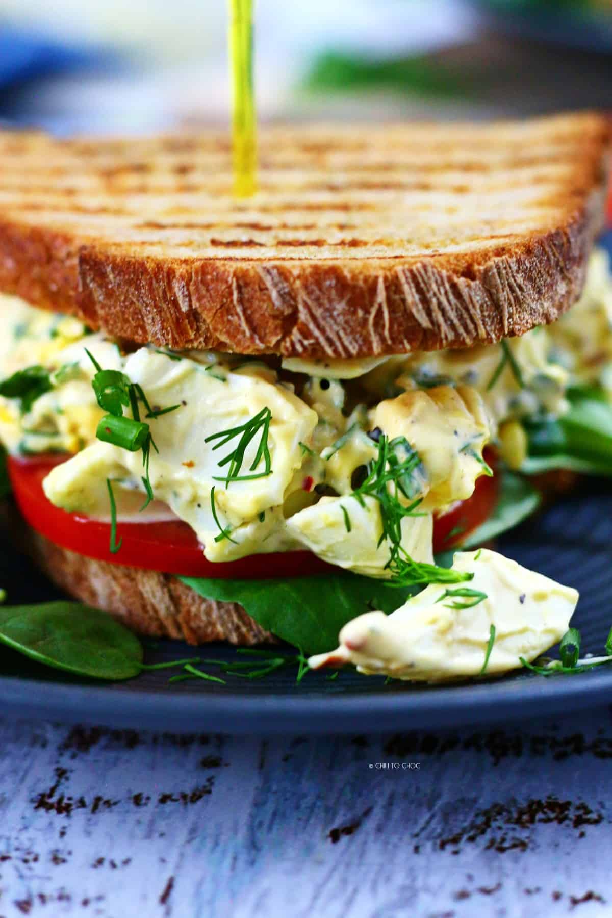 Closeup of the boiled egg sandwich garnished with chives and dill.