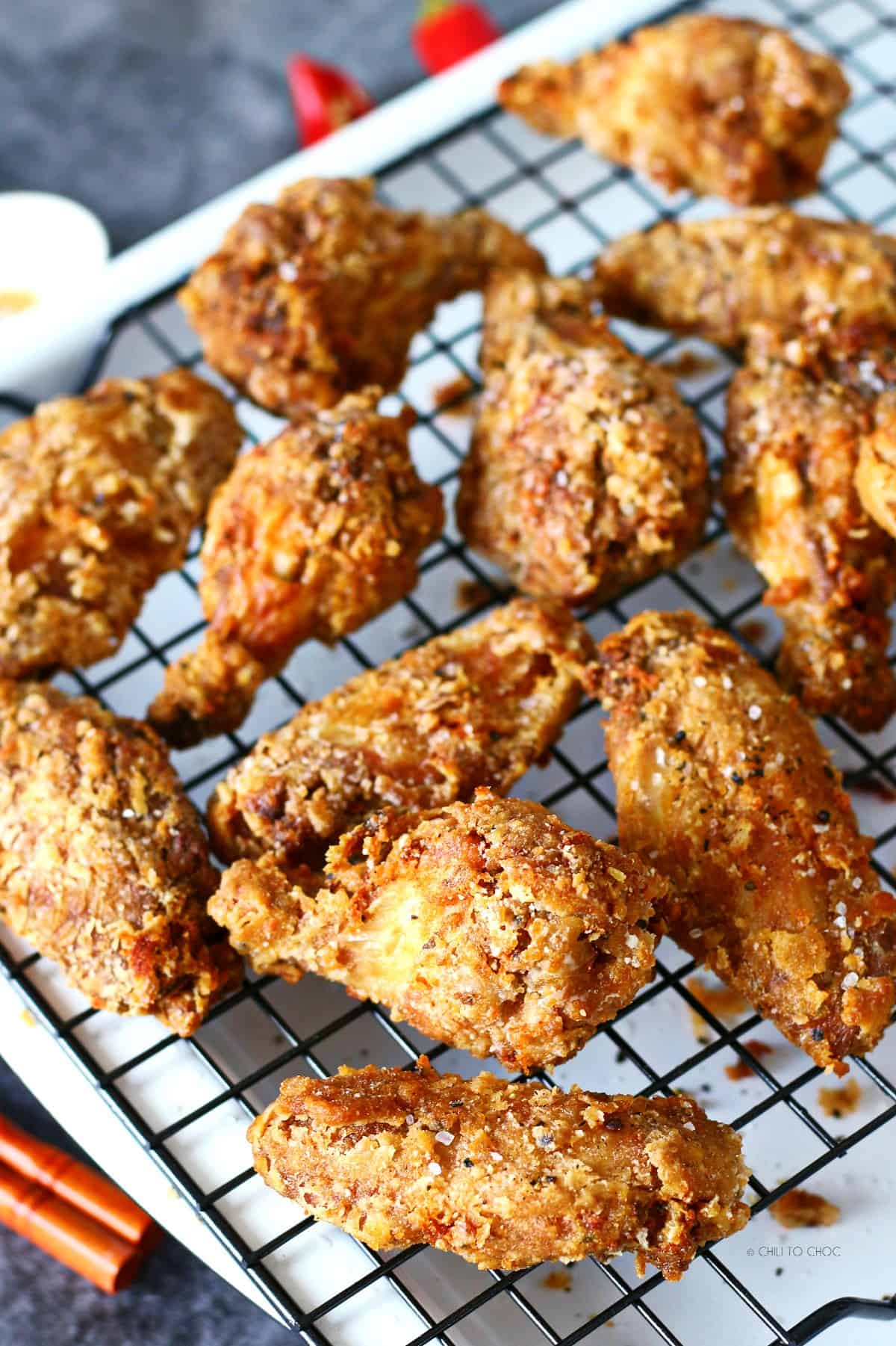 Deep fried chicken wings on a wire rack.