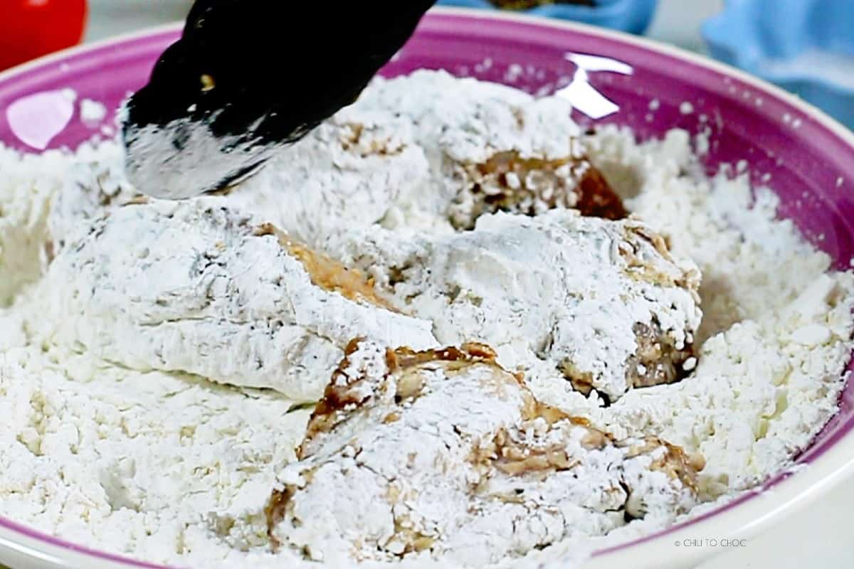 Chicken wings in a dredging mixture.