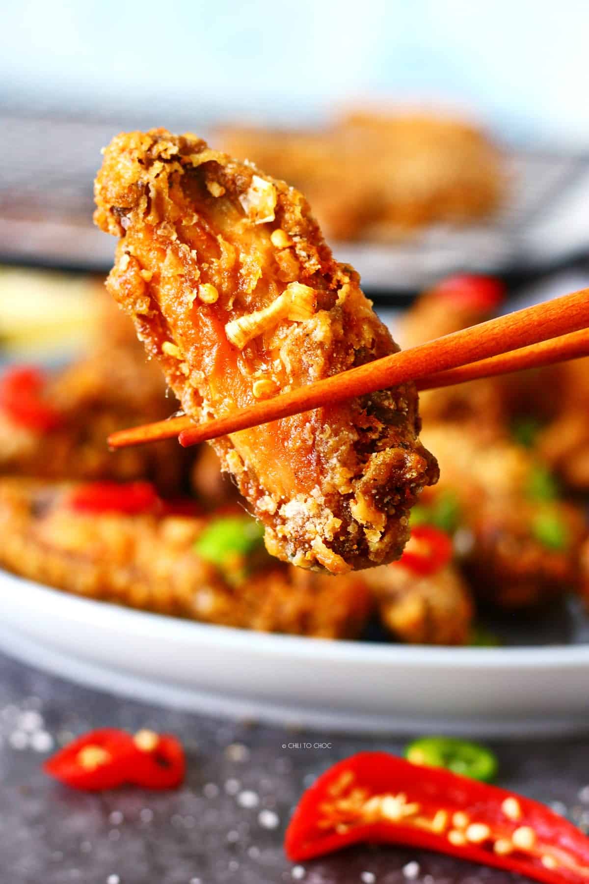Holding salt and pepper chicken wing with a chopstick.