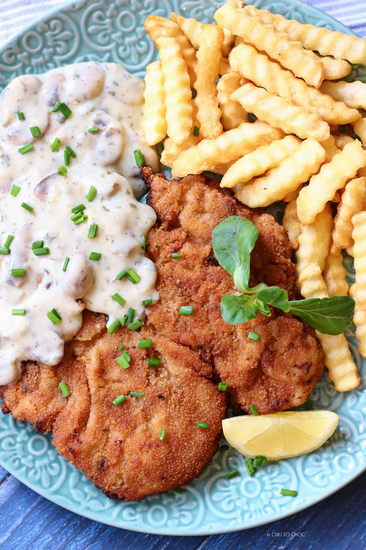Chicken schnitzel with mushroom sauce and fries.