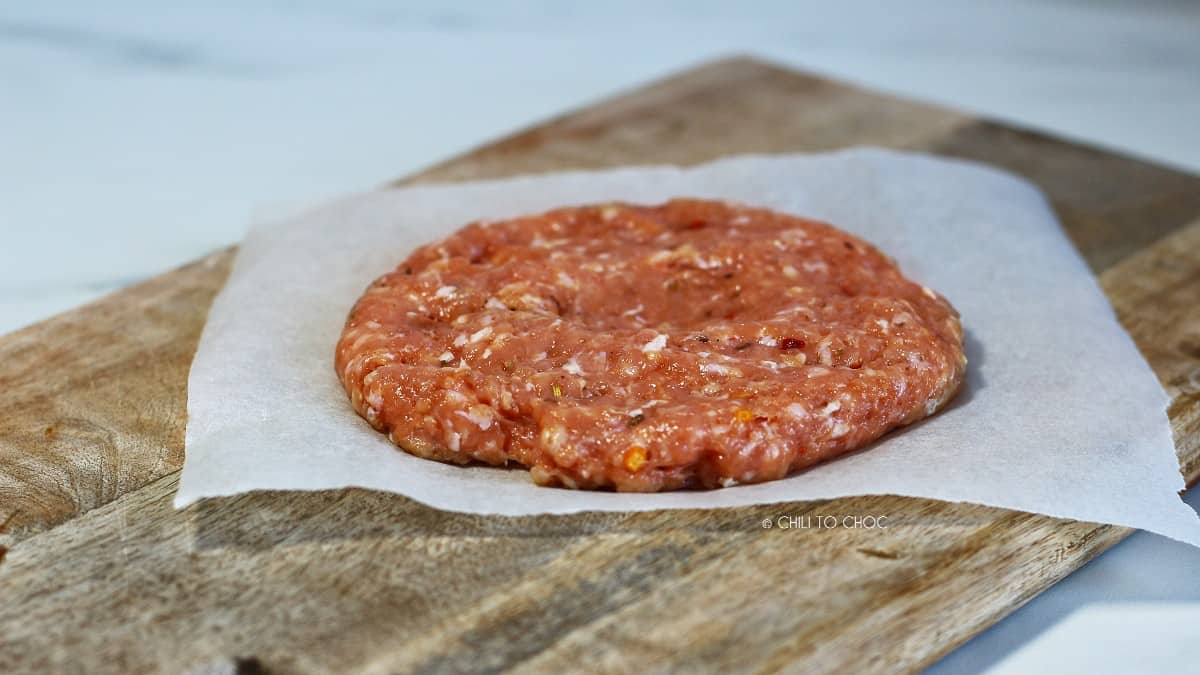 Raw hamburger patty on a butter paper.