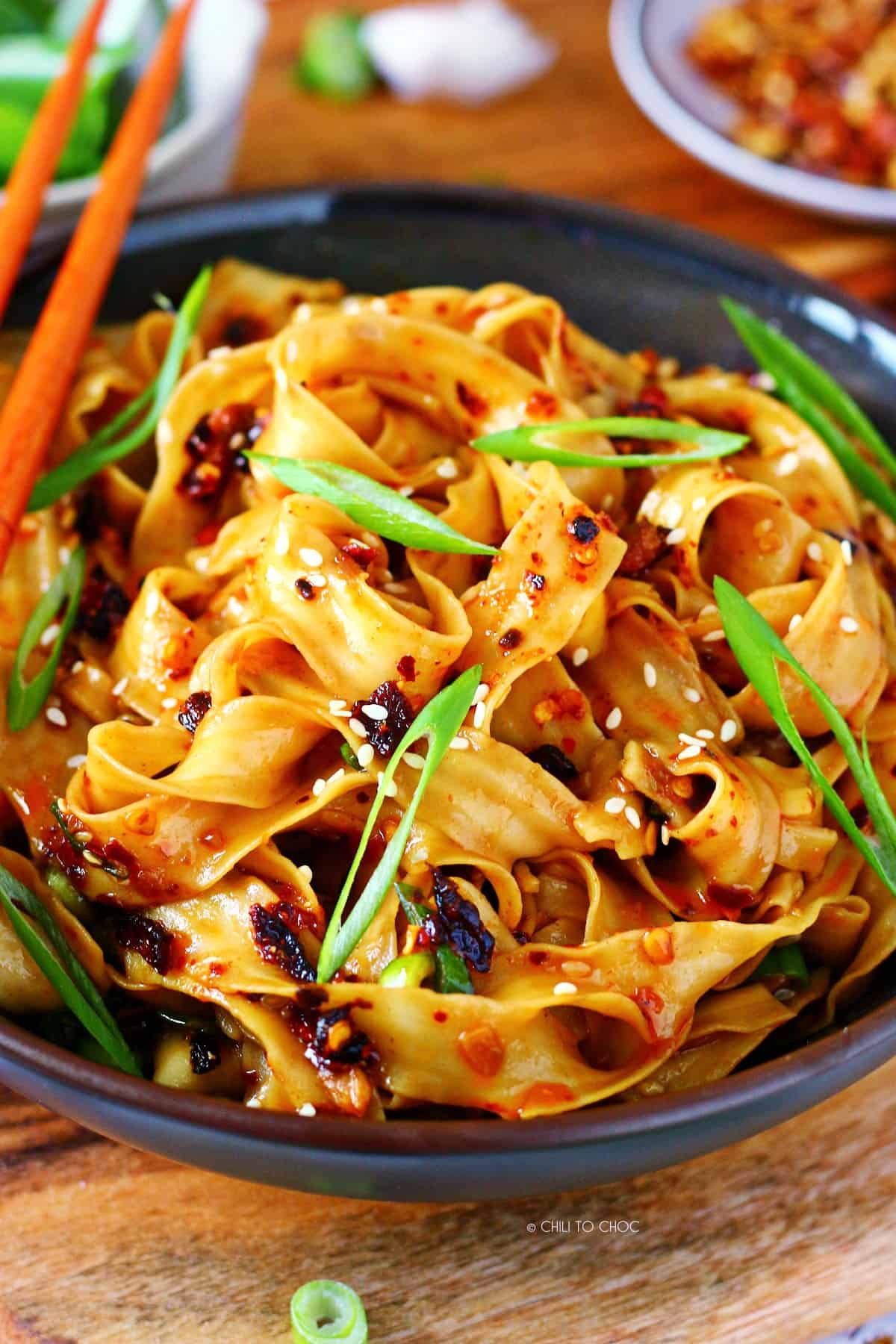 Garlic chili oil noodles garnished with sesame seeds and sliced green onions.