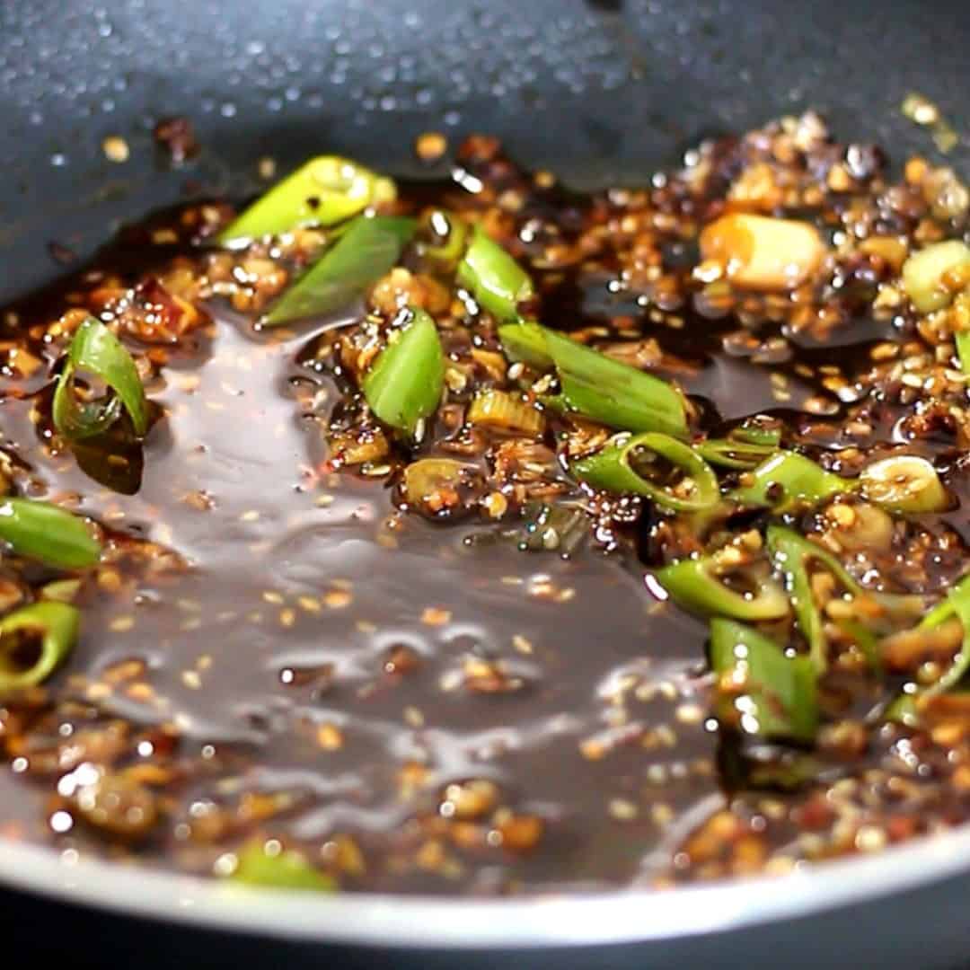 Sauces combined with chili oil and green onion in a pan.