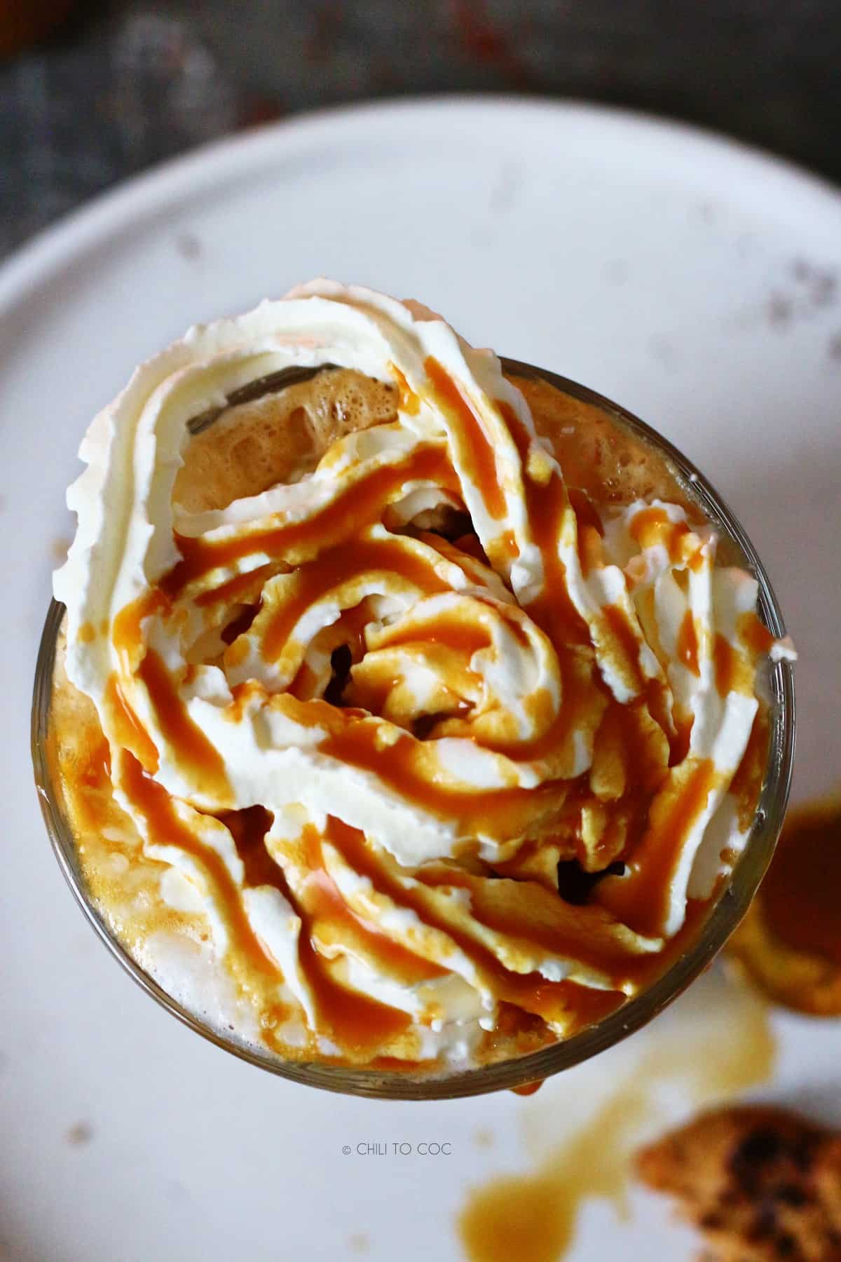 Overhead shot of latte glass with whipped cream and caramel sauce.