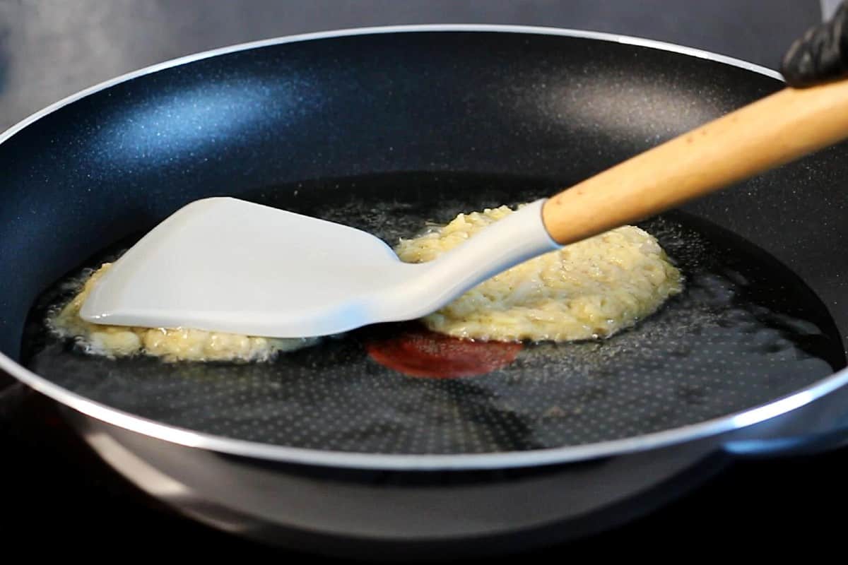 Pressing potato patty with a spatula.
