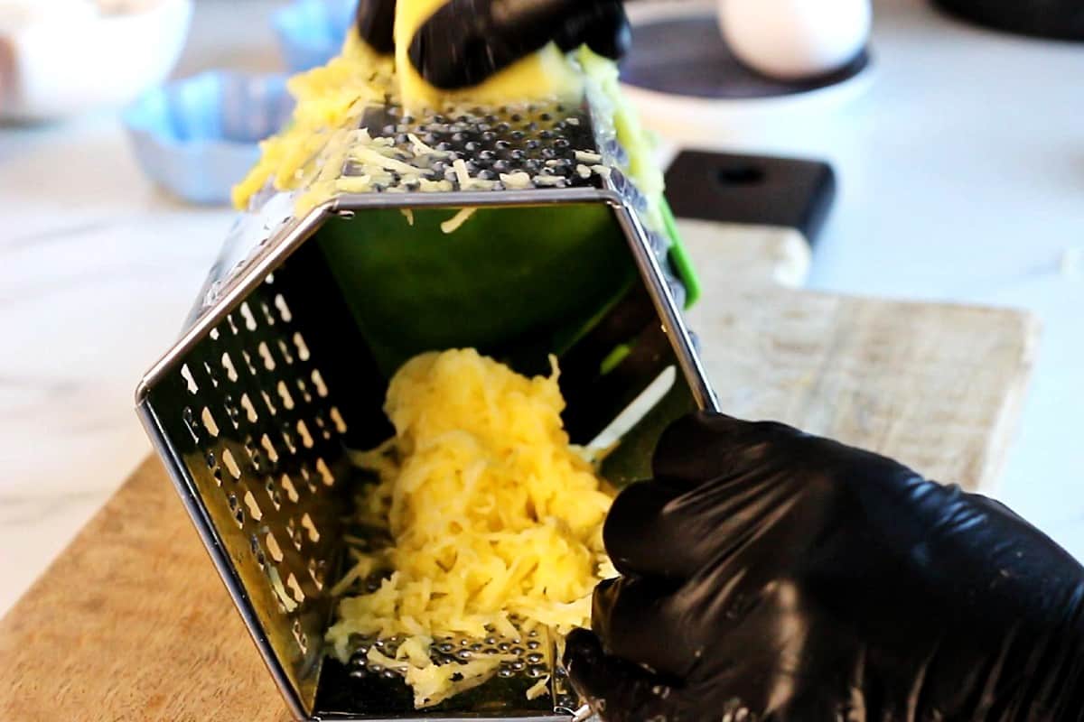 Shredding a potato on a box grater.