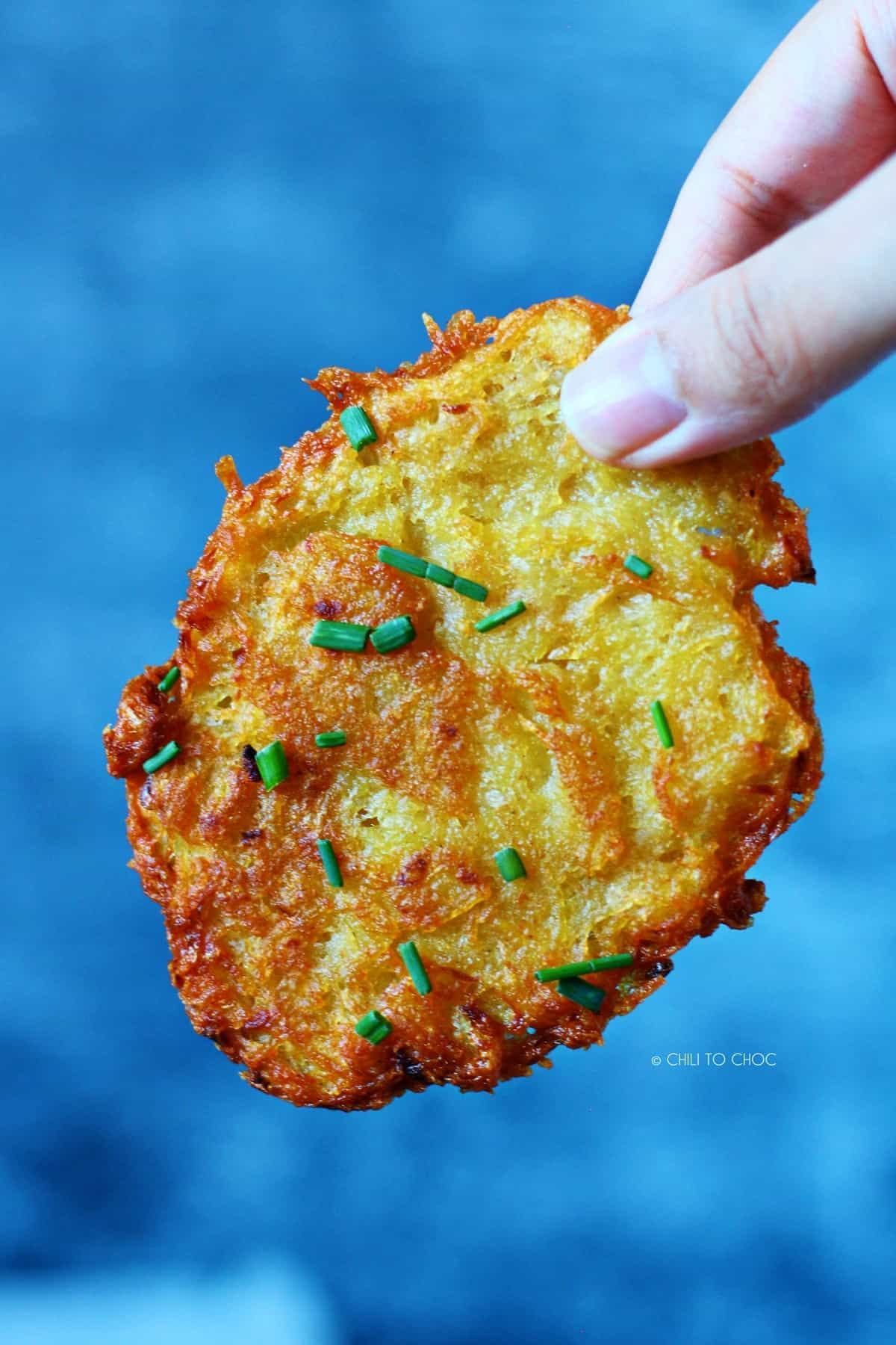 Holding one potato fritter.