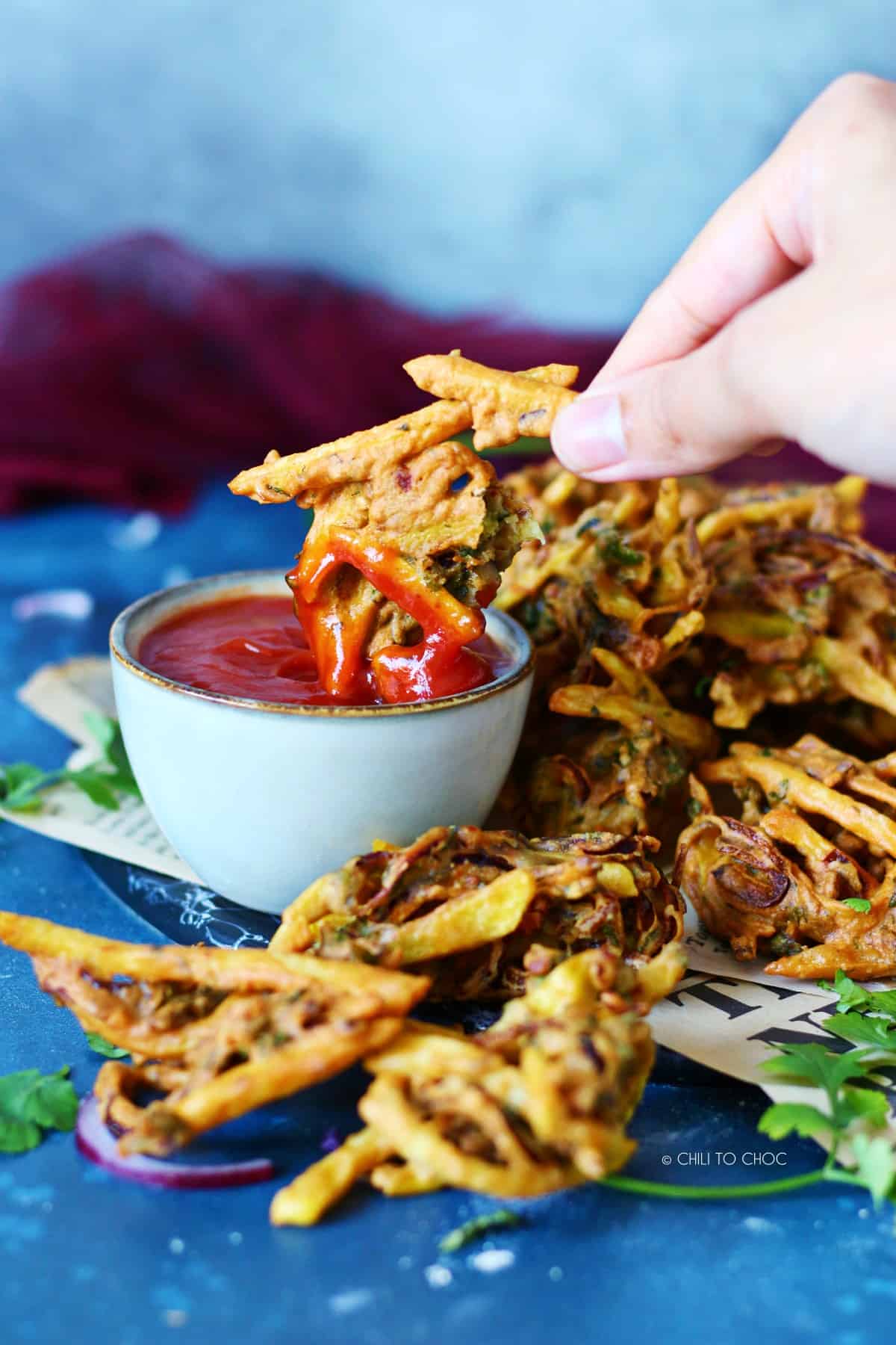 Dipping a piece of pakora in ketchup.